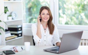 Woman smiling at laptop working from home at her own part time business.
